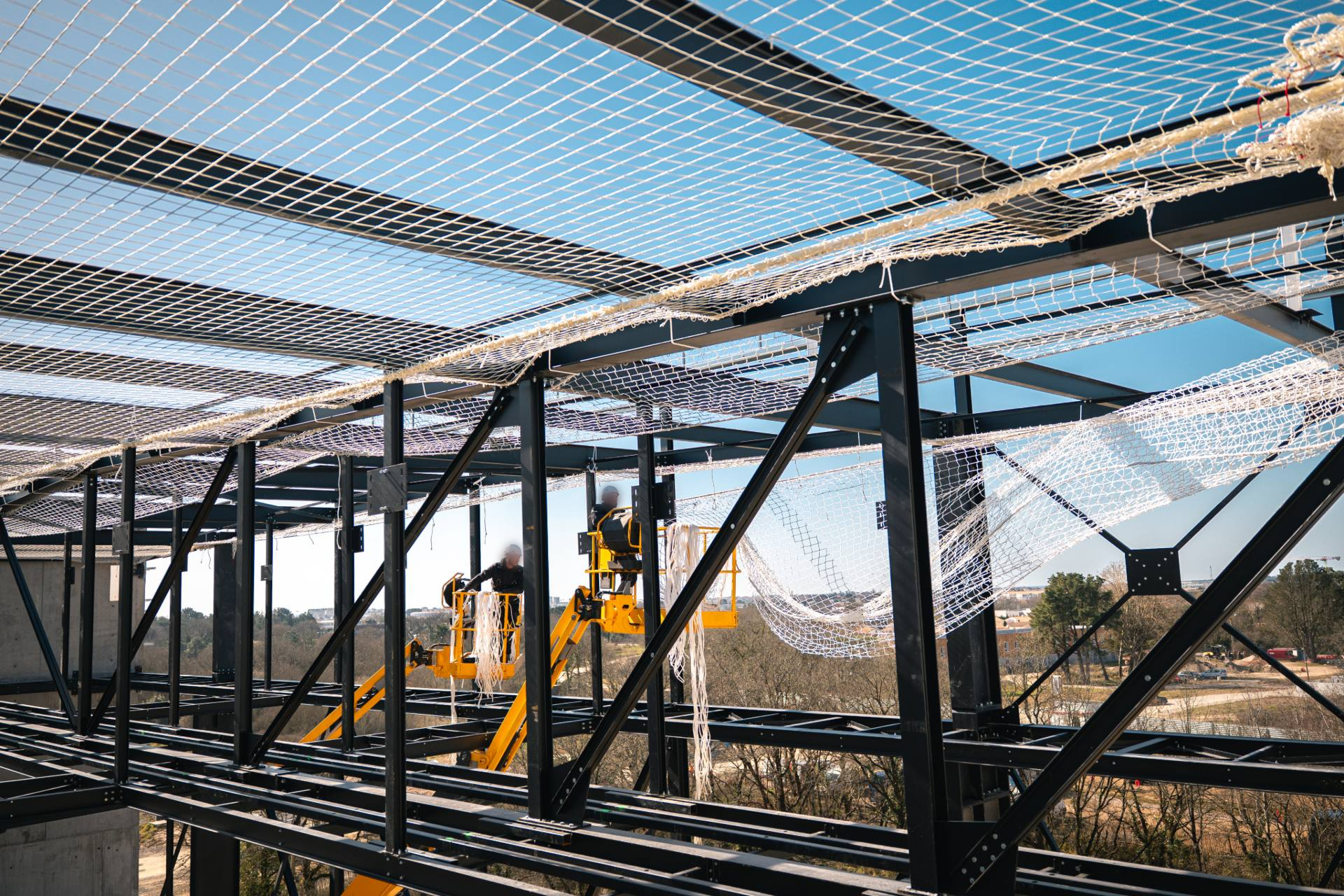 Deux ouvriers installant un filet de protection sur un chantier de construction
